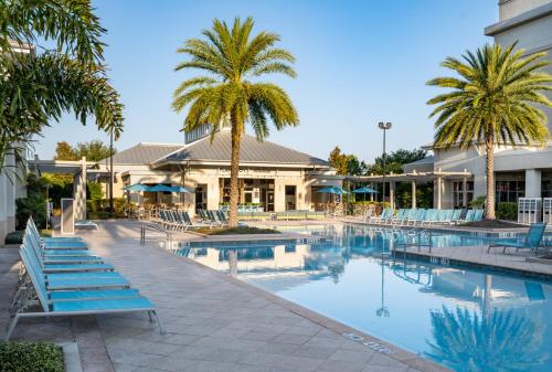 a swimming pool with blue chairs and palm trees at TownePlace Suites Orlando at FLAMINGO CROSSINGS® Town Center/Western Entrance in Orlando
