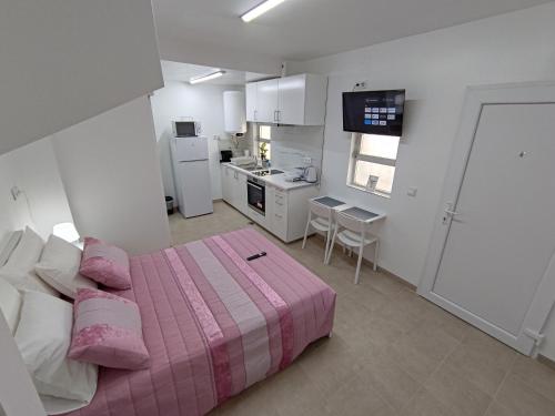 a bedroom with a pink bed and a kitchen at Room Dream Beato in Lisbon