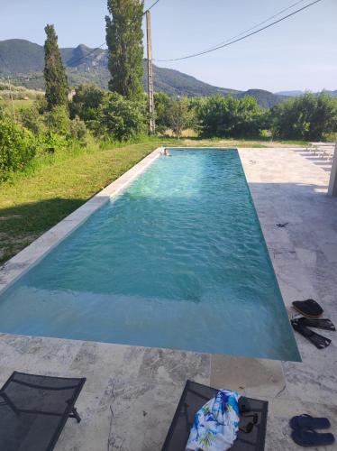 une piscine avec de l'eau bleue et des montagnes en arrière-plan dans l'établissement Terre de Lumière, à Nyons