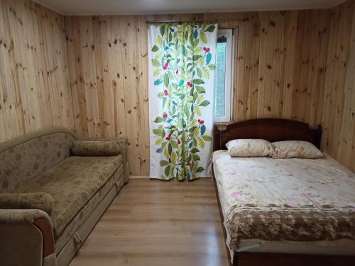 um quarto com uma cama, um sofá e uma janela em Еко-садиба БАКОТА em Kolodiyevka