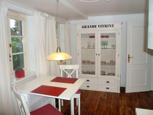 ein Esszimmer mit einem weißen Tisch und einem weißen Schrank in der Unterkunft Friesenhaus, App. 3 in Westerland