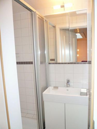 ein weißes Bad mit einem Waschbecken und einer Dusche in der Unterkunft Friesenhaus, App. 3 in Westerland