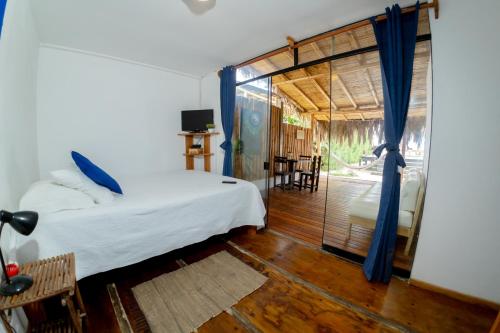 a bedroom with a bed and a sliding glass door at Casa Lodge (primera fila) in Vichayito