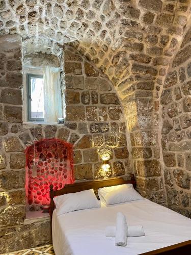 a bedroom with a bed in a stone wall at Hebi house in ‘Akko