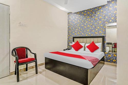 a bedroom with a bed and a red chair at OYO Flagship Hotel Smbha Palace in Mumbai