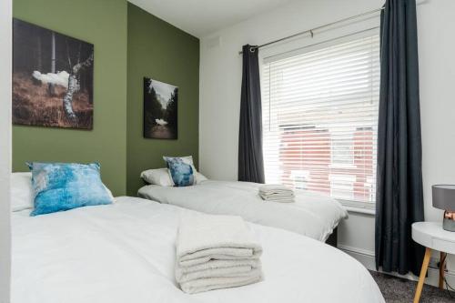 two beds in a room with green walls and a window at Manchester Urban Chic Hideaway in Manchester