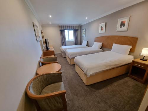 Habitación de hotel con 2 camas y sofá en Kegworth Hotel & Conference Centre, en Castle Donington