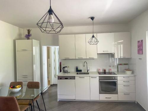a kitchen with white cabinets and a glass table at Tijara Apartment in Rijeka