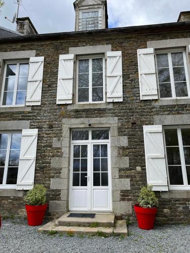 a brick house with white doors and two potted plants at La Maison des Amis en Normandie in Pontfarcy