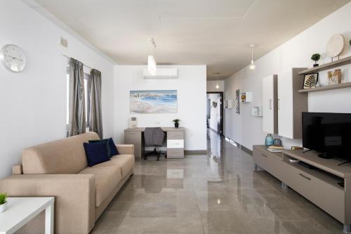 - un salon avec un canapé et une télévision dans l'établissement Hilltop Apartments - Stylish Comfort Living close to the sea, Bugibba, à San Pawl il-Baħar