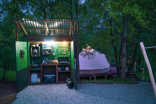 a small green building with a tent in the woods at Yatu Ecological Glamping in Drábsko