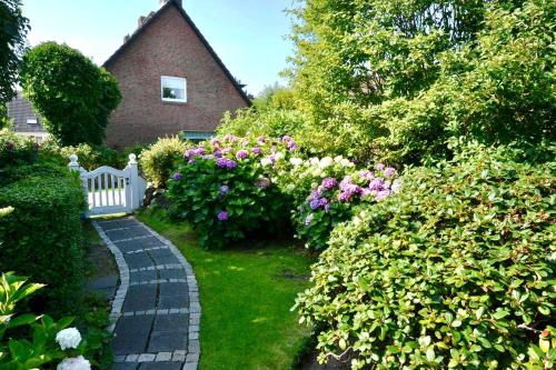 einen Garten mit Blumen und einem weißen Zaun und einem Haus in der Unterkunft Mövennest in Westerland