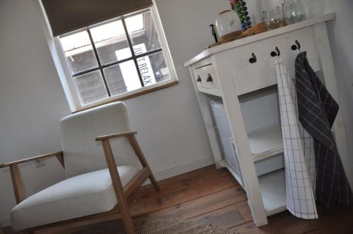 a room with a chair and a shelf and a window at Bed & Breakfast de Hoefstal in Noord-Sleen