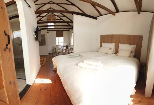 um quarto com uma grande cama branca e pisos em madeira em Bed & Breakfast de Hoefstal em Noord-Sleen