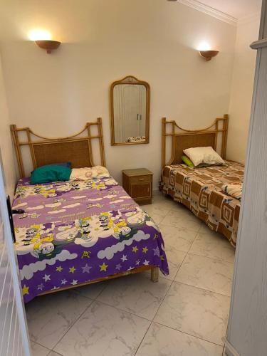 a bedroom with two beds and a mirror at Marina in El Alamein