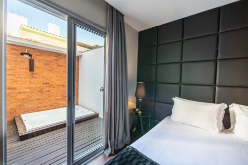 a bedroom with a bed and a balcony with a tub at Brut by Slaviero Hotéis in Balneário Camboriú