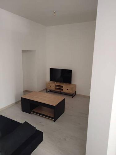 ein Wohnzimmer mit einem TV und einem Couchtisch in der Unterkunft Appartement cœur de ville in Tréguier