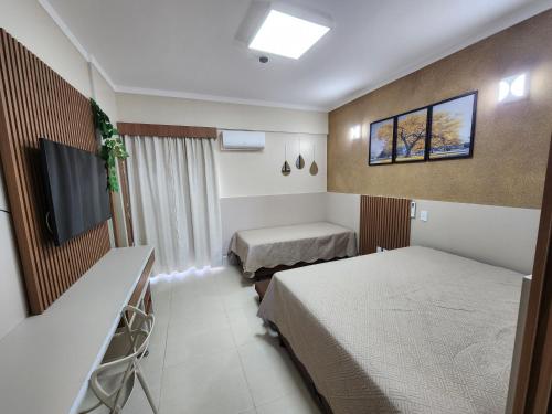 um quarto de hotel com duas camas e uma televisão de ecrã plano em Spazzio diRoma - Apartamentos JN em Caldas Novas