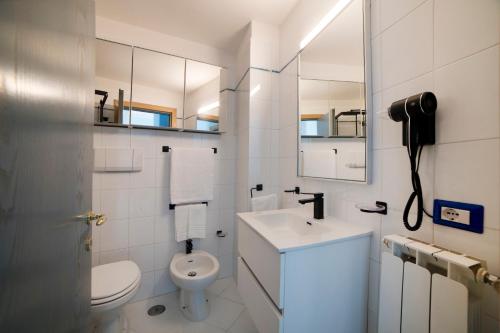 a white bathroom with a sink and a toilet at Vento Verde Apartments in Sperlonga