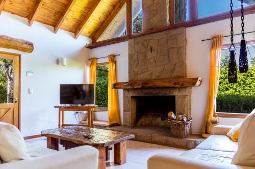 - un salon avec une cheminée en pierre dans l'établissement BOG Casa Glorieta - casa 4 cuartos, à Villa La Angostura