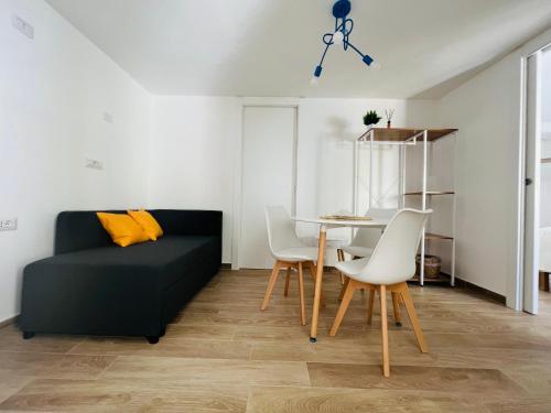 uma sala de estar com um sofá, uma mesa e cadeiras em Via Giardini Rooms em Villasimius