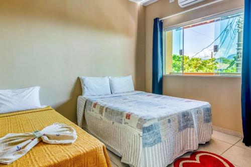 1 dormitorio con 2 camas y ventana en Chalés Ilhabela Esmeralda, en Ilhabela