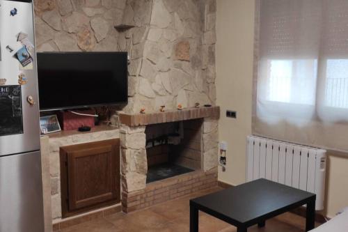 AscóにあるCa Serrulletaの石造りの暖炉と薄型テレビのあるリビングルーム