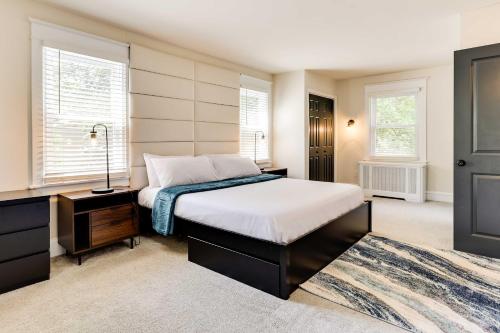 a bedroom with a bed and a dresser and two windows at Folcroft Vacation Rental about 10 Mi to Philadelphia! 