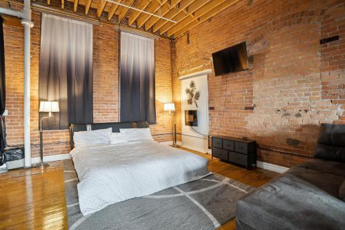 a bedroom with a bed and a brick wall at Idlewild Villa Loft apts in Detroit