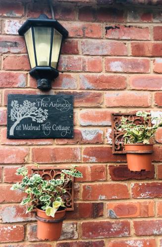 a brick wall with two potted plants and a street light at The Annexe at Walnut Tree Cottage in Hope under Dinmore