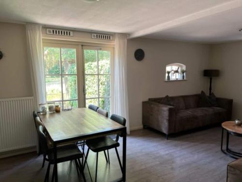 a living room with a table and a couch at Restful Holiday Home with a Private Terrace and hottub in Veendam