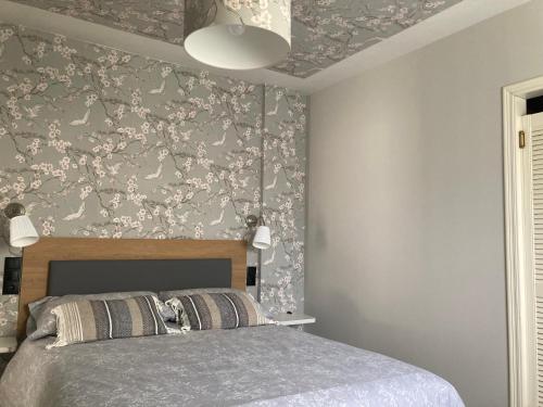 a bedroom with a bed with a floral wallpaper at Luarca Experience in Luarca