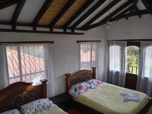 1 dormitorio con 2 camas y 2 ventanas en Finca villa Claudia a 25 min de villa de Leyva, en Villa de Leyva