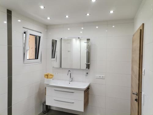 bagno bianco con lavandino e specchio di Ferienwohnung Pilgram-Huber ad Afritz