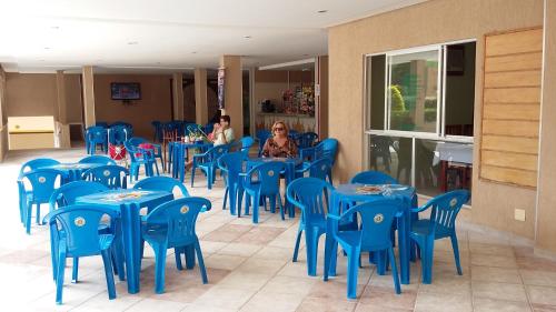 two women sitting at tables in a restaurant with blue chairs at Prive das Thermas 405 in Caldas Novas