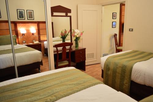 a hotel room with two beds and a mirror at Comfort Hotel Suites in Amman