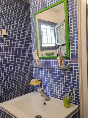 a blue tiled bathroom with a sink and a mirror at Le Loft in Montpellier