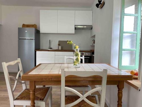 een keuken met een houten tafel en een vaas met bloemen erop bij House in idyllic village between vineyards and sea in Saint-Pons-de-Mauchiens