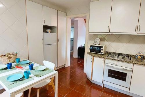 a kitchen with white cabinets and a table with blue dishes on it at Casinha de Padrões in Venda Nova
