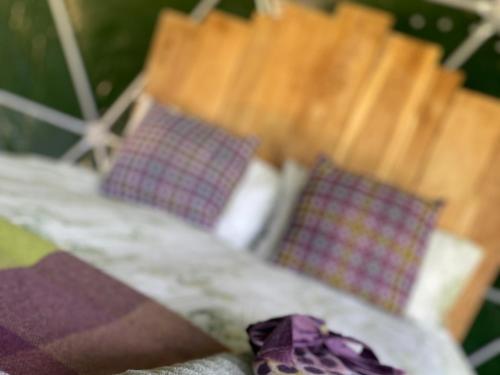 a bed with four pillows on it with a purple blanket at Geodesic Dome Glamping in Llanidloes
