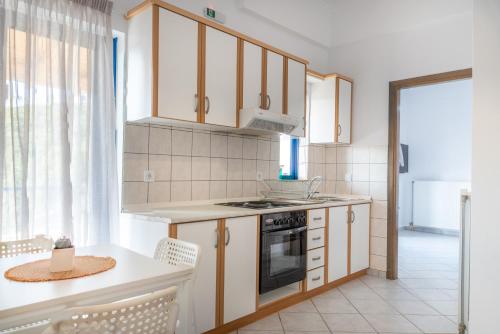 uma cozinha com armários brancos e um forno com placa de fogão em Villa Rodanthi Sivota em Sivota