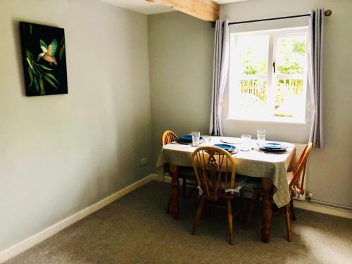a dining room with a table with chairs and a window at The Annexe at Walnut Tree Cottage in Hope under Dinmore