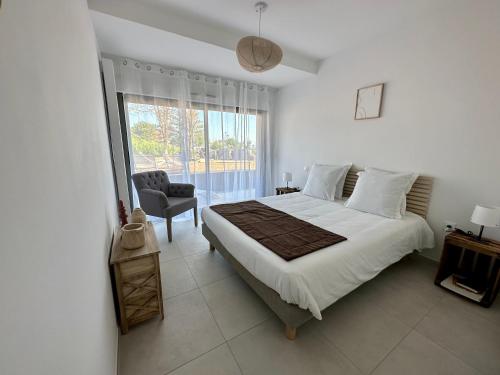 a bedroom with a bed and a chair and a window at La Baie des 2 Caps in Tardinghen