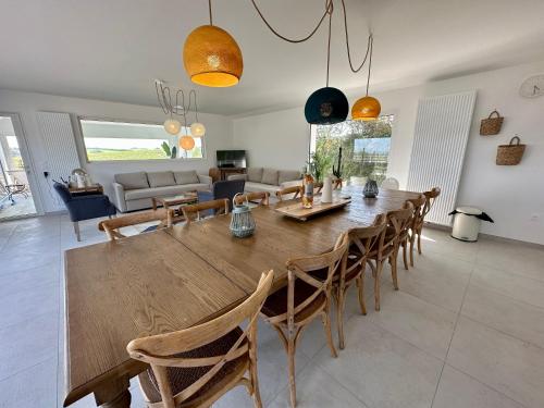 a dining room and living room with a wooden table and chairs at La Baie des 2 Caps in Tardinghen