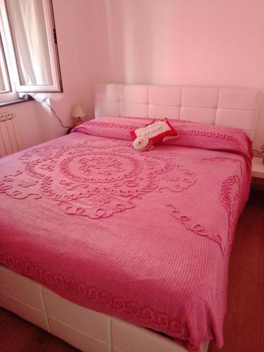 a pink bed with a teddy bear sitting on it at Da qui, il mare in Genova