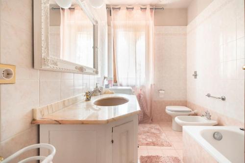 ein Badezimmer mit einem Waschbecken, einem WC und einem Spiegel in der Unterkunft Fiorenza House in Luisago