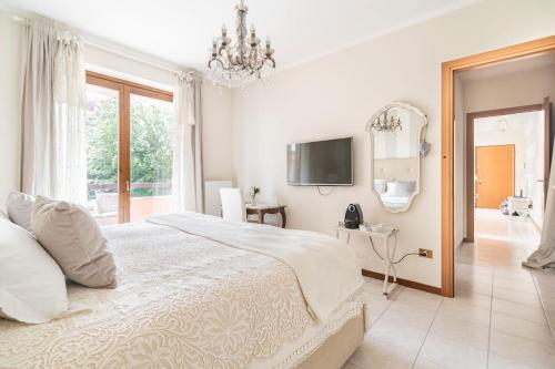 a white bedroom with a large bed and a television at Fiorenza House in Luisago