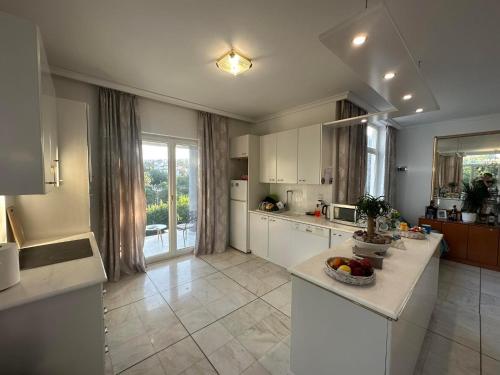 a large kitchen with white cabinets and a large window at Serenade luxury villa in Koskinou