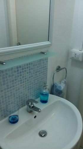 ein Badezimmerwaschbecken mit Spiegel und einem Glas darauf in der Unterkunft Damarilù in Alghero
