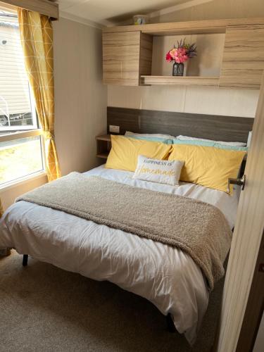 a bedroom with a large bed with yellow pillows at Beautiful caravan in Trecco Bay! 74 sycomore in Bridgend
